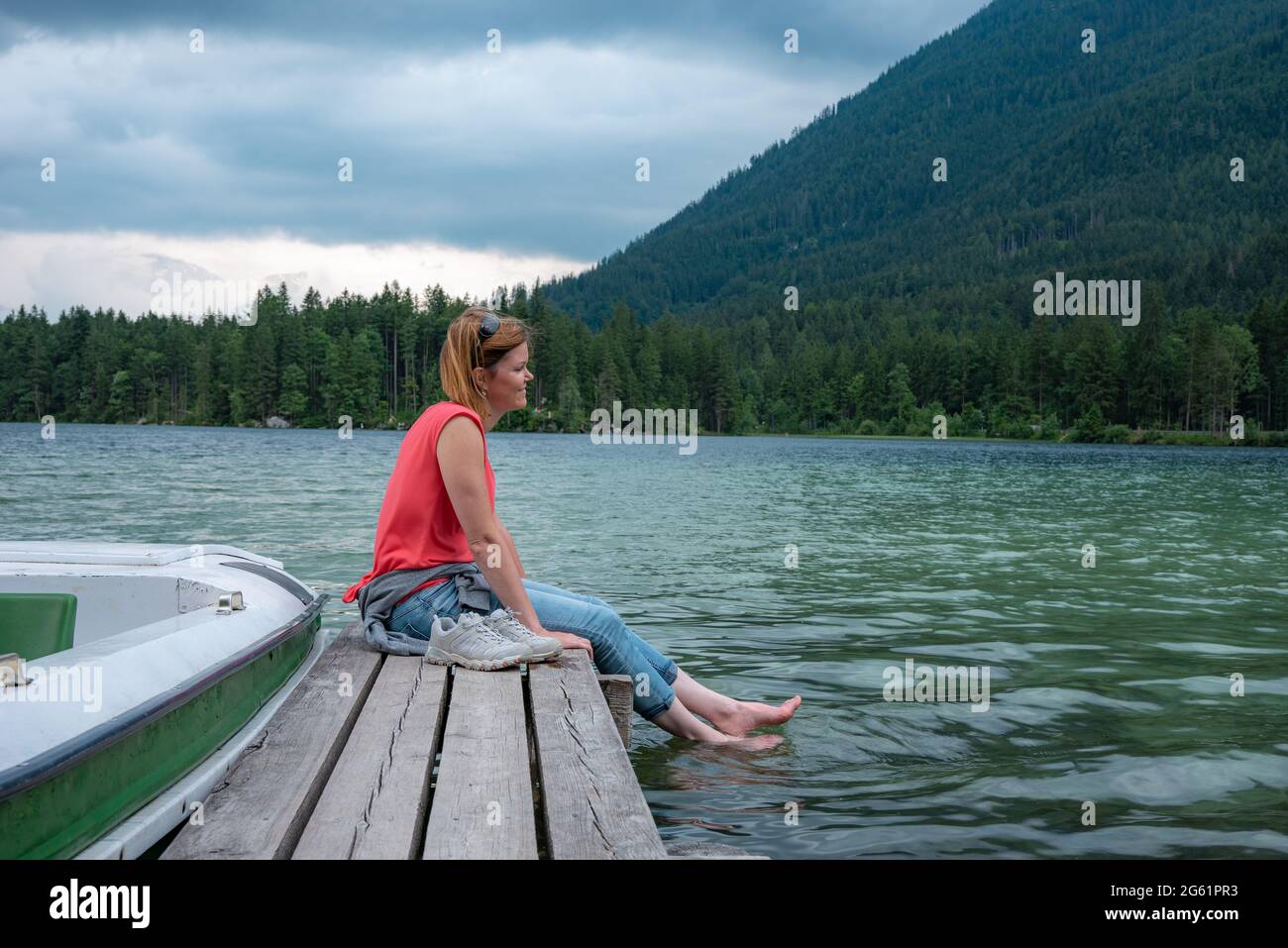 Junge Frau, die sich am Pier am See entspannt Stockfoto