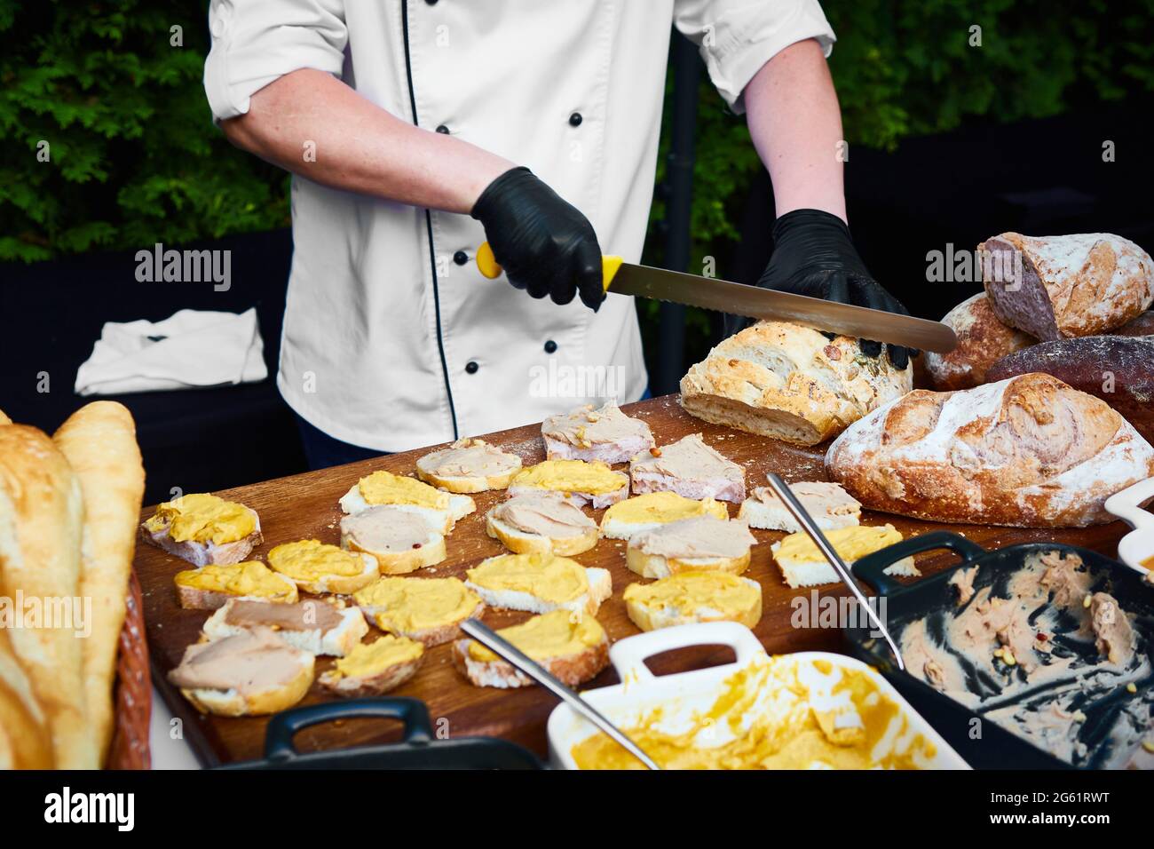 Im mittleren Teil hackt der Kellner Brötchen auf dem Schneidebrett bei einer Veranstaltung im Freien Stockfoto