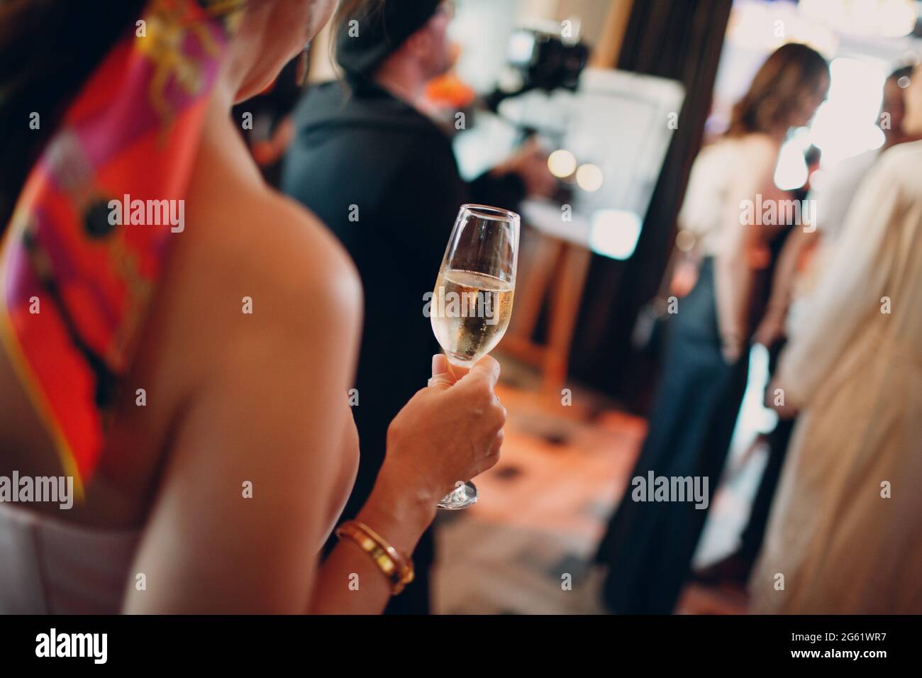 Rückansicht Frau hält bei der Party ein nebelig gekühltes Glas Champagner in der Hand. Stockfoto