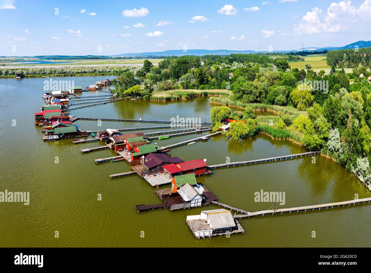 Luftaufnahme des berühmten schwimmenden Dorfes Bokod mit Piers und traditionellen Fischerhütten aus Holz, die am See Bokodi gebaut wurden. Stockfoto