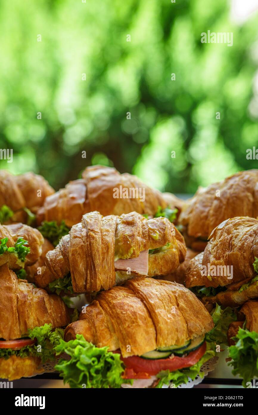 Sandwiches mit Croissants, Schinken, Tomaten und Salat. Viele leckere schnelle gesunde Lebensmittel. Snack bei der Veranstaltung. Stockfoto