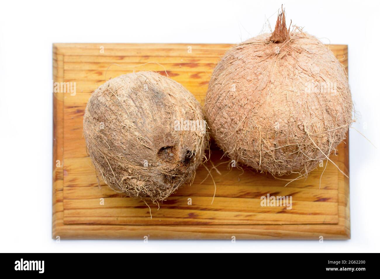 Ganze Kokosnüsse auf einem Holzbrett auf weißem Hintergrund. Tropische Früchte aus der Karibik Stockfoto