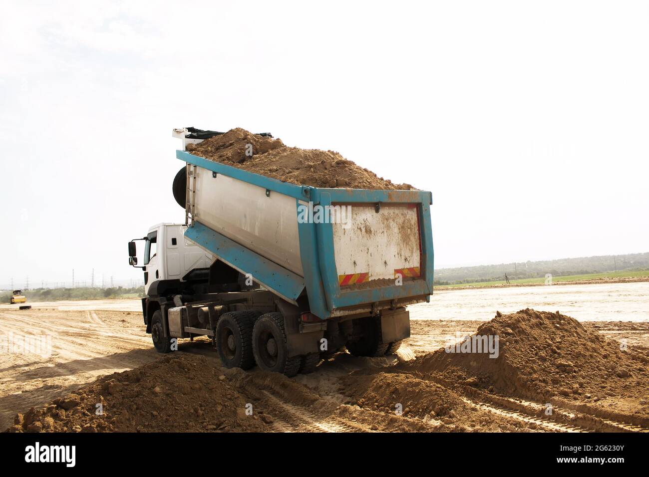 Muldenkipper entlädt Tonerde für den Bau einer neuen Autobahn. Lehm für die Grundlegung einer neuen Straße. Stockfoto