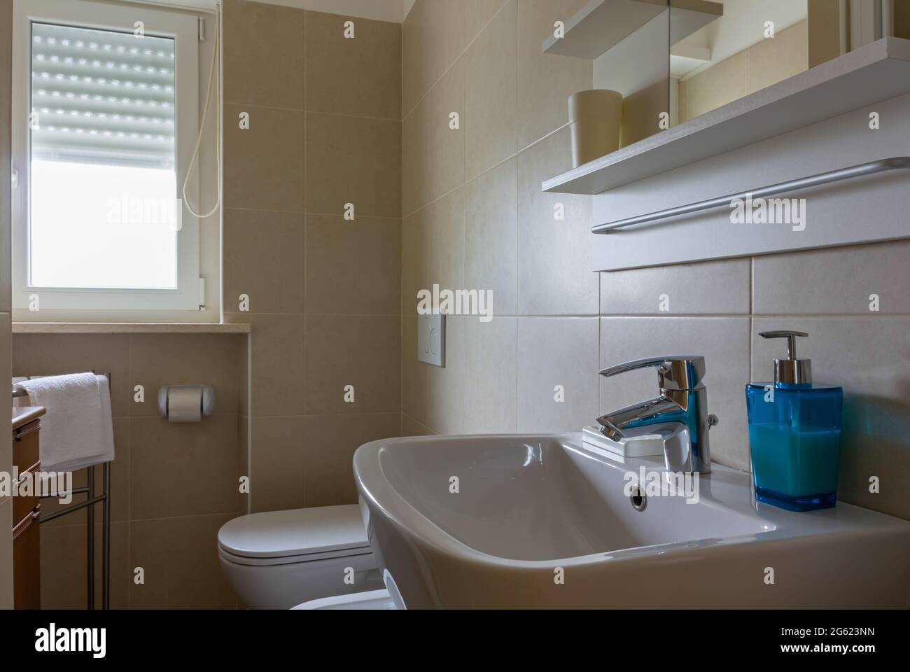 Kleines, elegantes gefliestes Badezimmer, das von Tageslicht erhellt wird Stockfoto