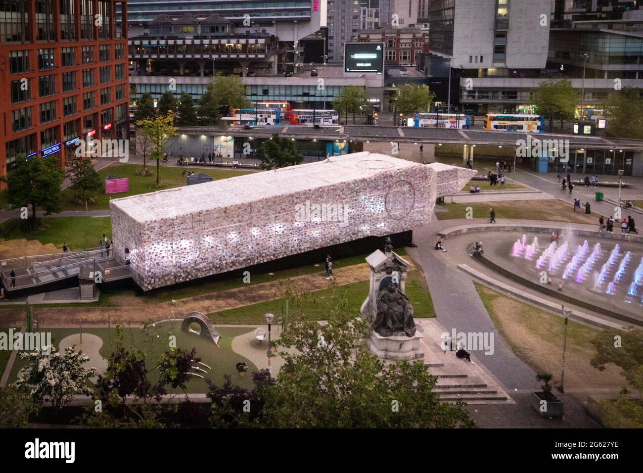 Manchester, Großbritannien. Juli 2021. MIF kehrt in die Stadt zurück. Die Installation Big Ben Lying Down der artistÊMarta Minuj'n ist offiziell in den Piccadilly Gardens eröffnet. Die 42 m lange Nachbildung von Big Ben ist in 20,000 Exemplaren von Büchern überdeckt, die die britische Politik geprägt haben und eine freudige Einladung für die Menschen sind, sich ihre nationalen Symbole neu zu denken und sich um Demokratie und Gleichheit zu vereinen. Das MIF ist ein von Künstlern angeführtes Festival, das neue Werke aus verschiedenen darstellenden Künsten, bildender Kunst und Populärkultur präsentiert. Kredit: Andy Barton/Alamy Live Nachrichten Stockfoto