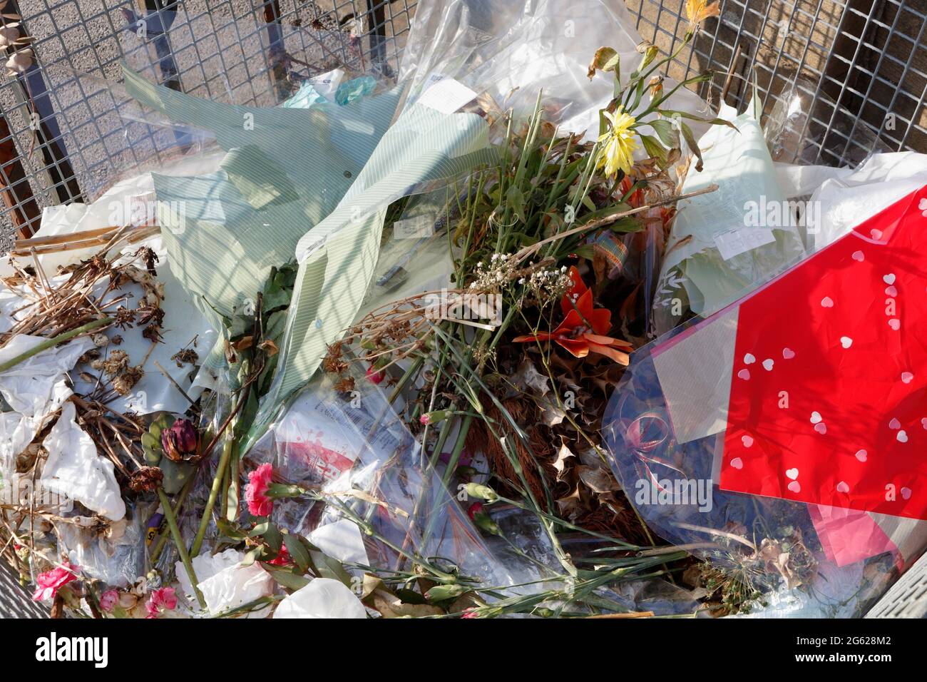 Abfalleimer auf einem Friedhof voller weggeworfener Blumen und Abfalleimer, Plastikverpackungen, Müll Stockfoto