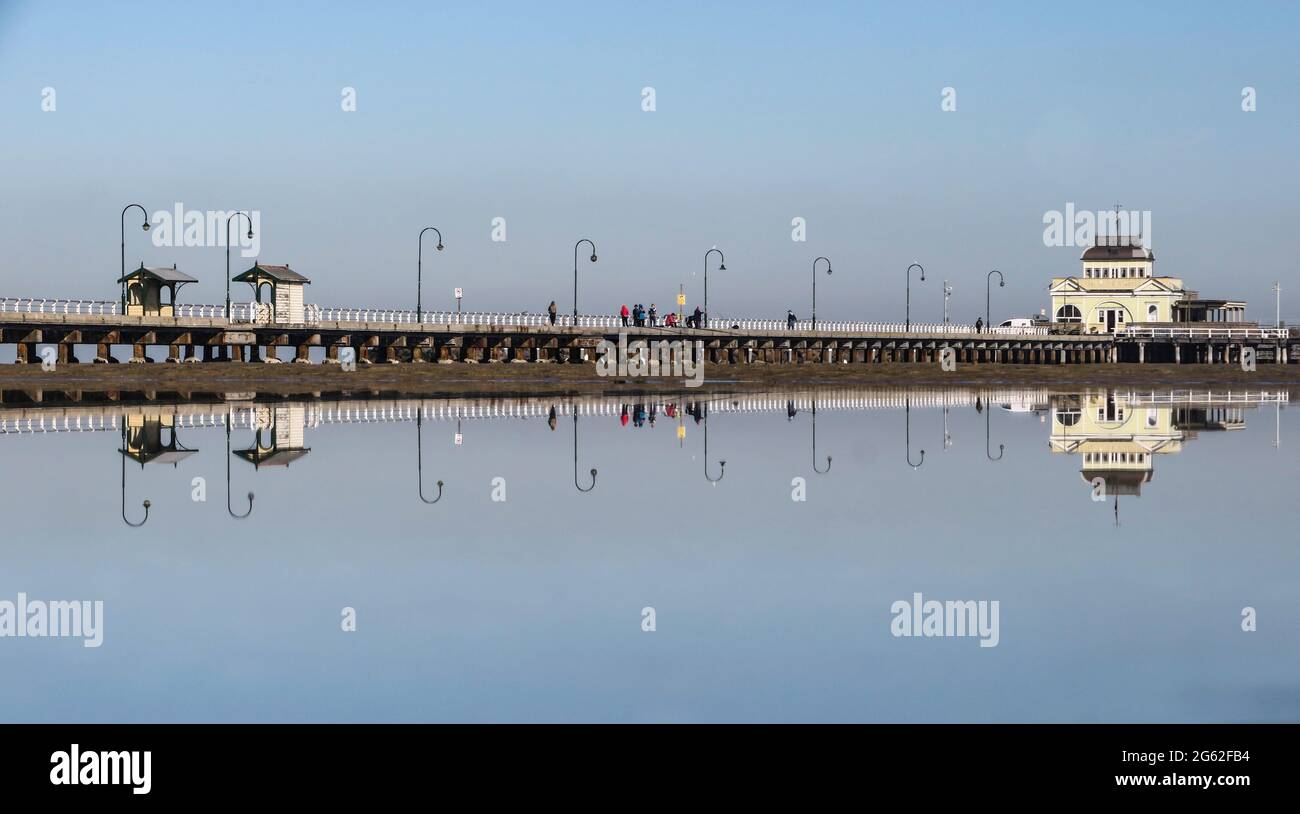 Melbourne Australien. Der historische St. Kilda Pier spiegelt sich in den stillen Gewässern der Port Phillip Bay wider. Stockfoto