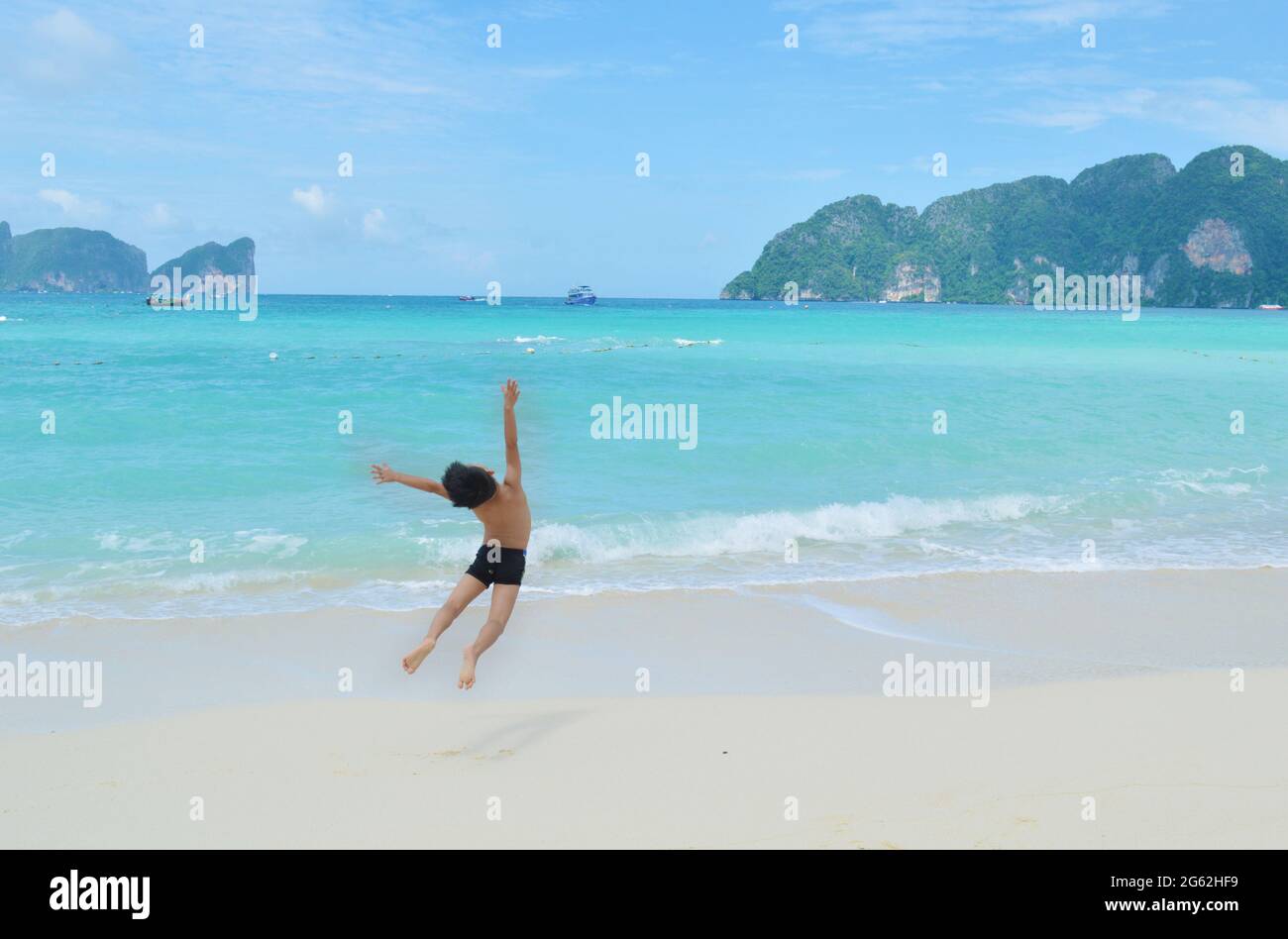 Kleiner Junge, der vor dem Koh Phi Phi Island Strand in Thailand springt Stockfoto