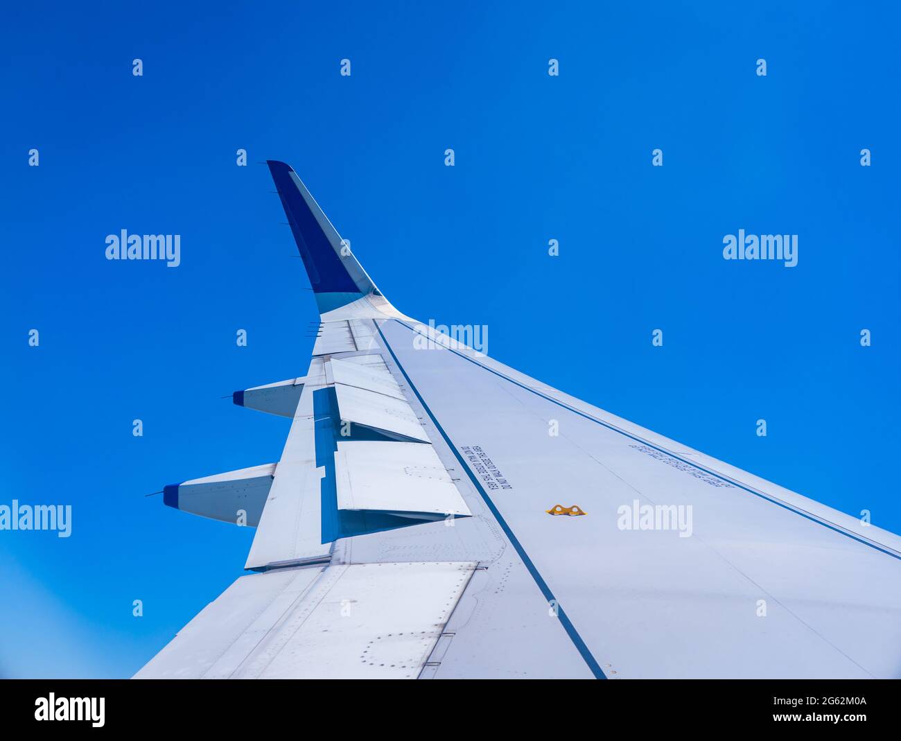 Eine Flugzeugflügelansicht mit ausgeklappten Klappen. Blauer Himmel im Hintergrund. Stockfoto