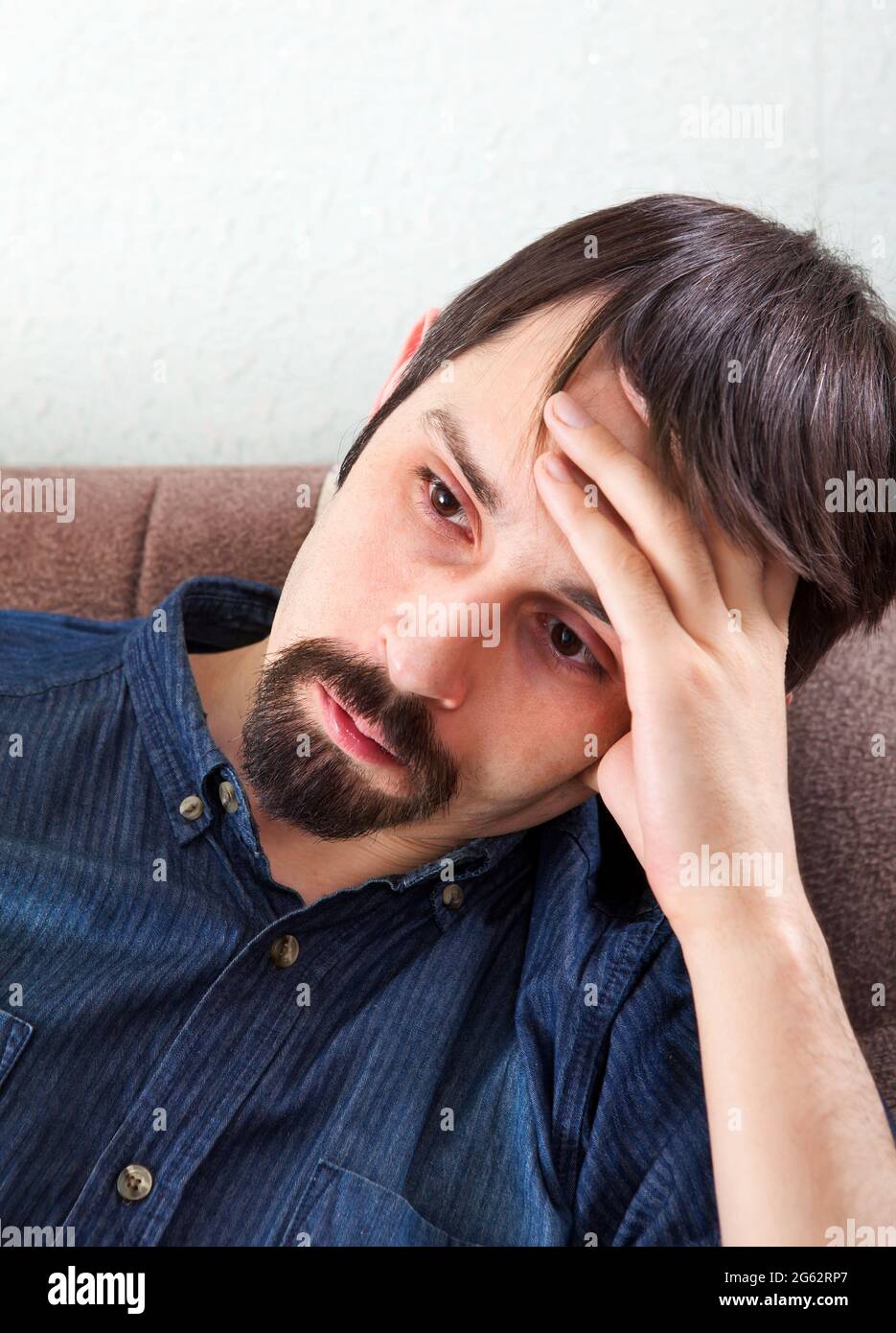 Trauriger junger Mann auf dem Sofa im Zimmer Stockfoto