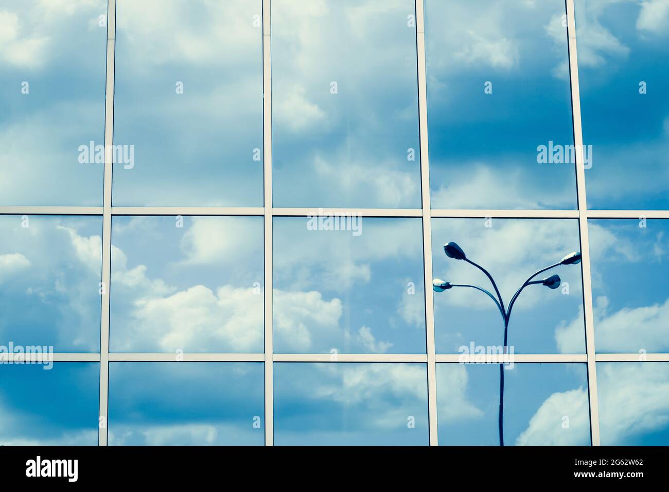 Verspiegelte Fenster, Spiegelung von Wolken und Laterne, blauer Himmel, Wolkenkratzer-Oberfläche. Linienmuster, Perspektive, Stahlstruktur, urbane Abstraktion. Geome Stockfoto