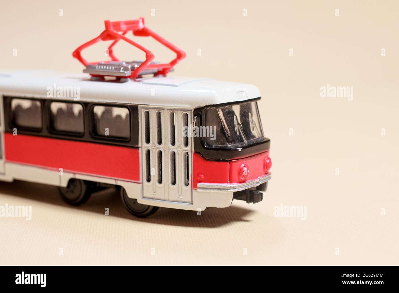 Kinderspielzeug rot weiß Tram auf einem beigen Hintergrund Kopie Platz für Text. Spielzeug für einen Spielwarenladen, Autos für einen Jungen. Stockfoto