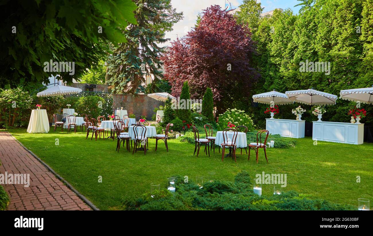 Runder Tisch mit weißen Tuch bedeckt und Stühle stehen auf einem grünen Rasen im Freien. Stockfoto