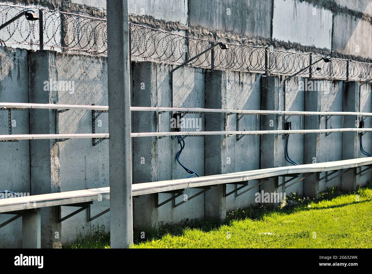Eine Betonwand mit Stacheldraht oben. Sonderzone. Streng geschütztes Objekt. Gefängnis oder Haftort Stockfoto