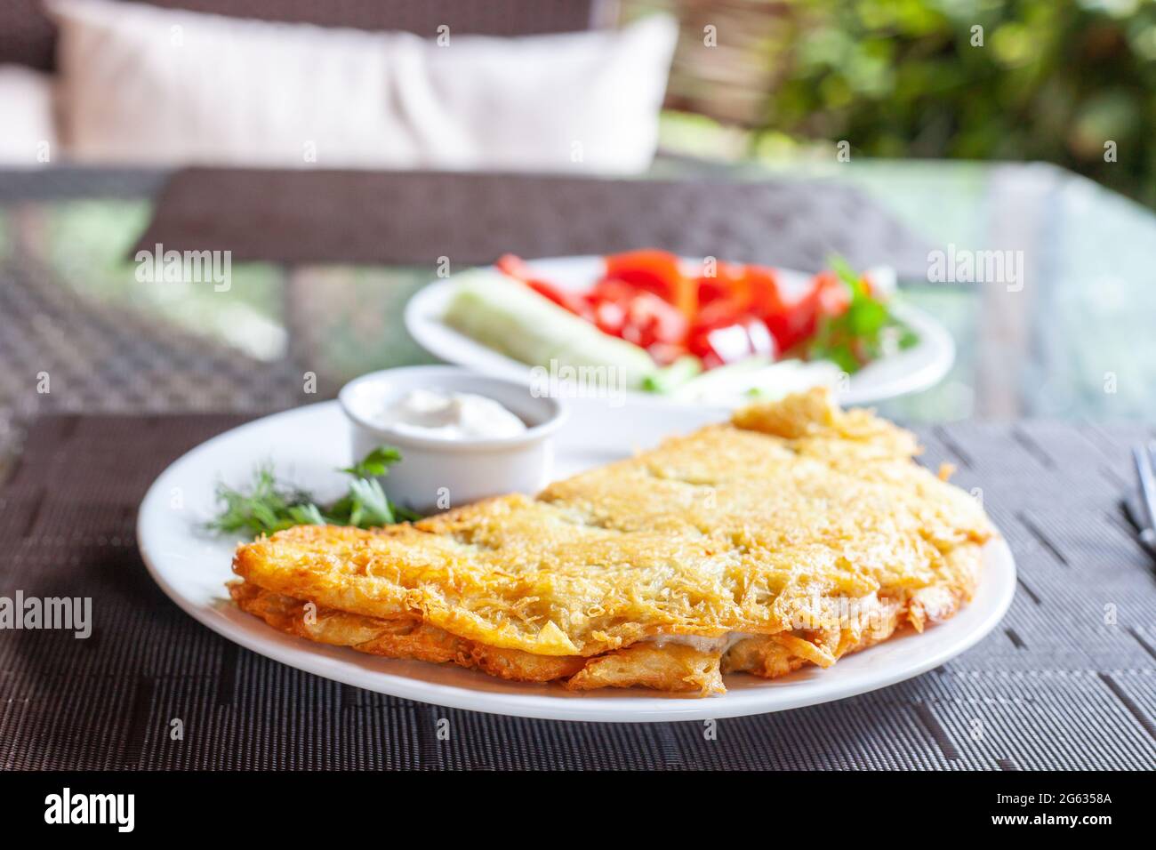 Großer Kartoffelpfannkuchen mit saurer Rahm. Deruny oder Draniki auf weißem Teller, ukrainisches Essen Stockfoto