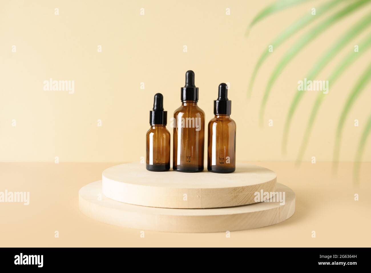 Minimale moderne Zusammensetzung mit Naturkosmetik und Serumöl in Flaschen auf Ständer auf beigem Hintergrund. SPA-Set für die Körperpflege. Stockfoto