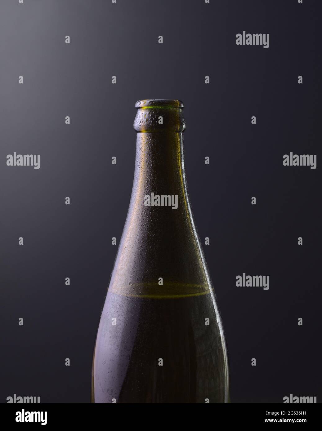 Vorderansicht einer Flasche kaltes Bier mit dunkelschwarzem Hintergrund und violetten Farbverläufen. Kaltes alkoholisches Getränk, internationales Biertagskonzept. Stockfoto