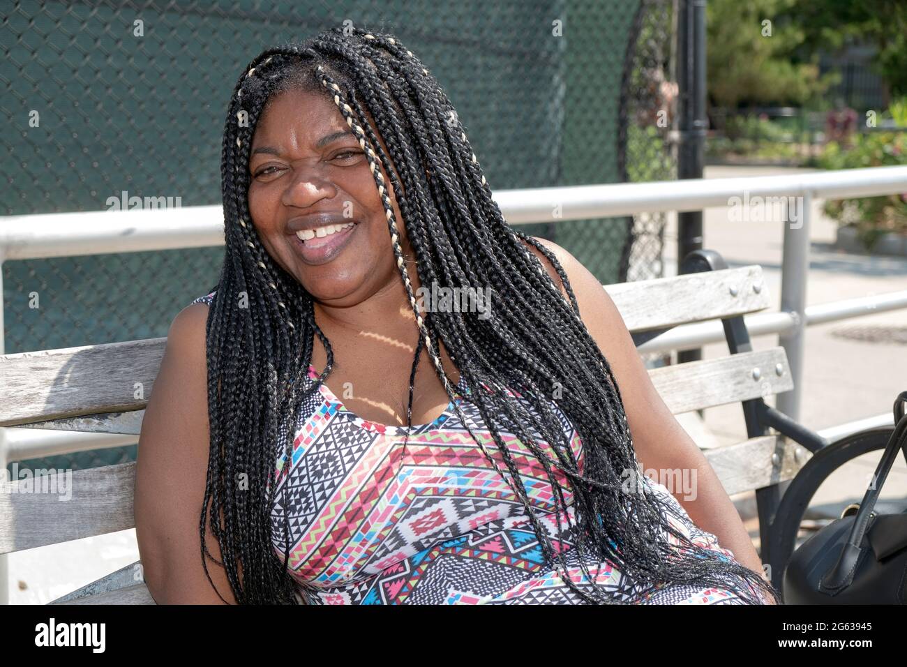 Posierte Porträt einer fröhlich lachenden attraktiven nigrischen Amerikanerin mit langen Haarverlängerung. In Brighton Beach, Brooklyn, New York City. Stockfoto