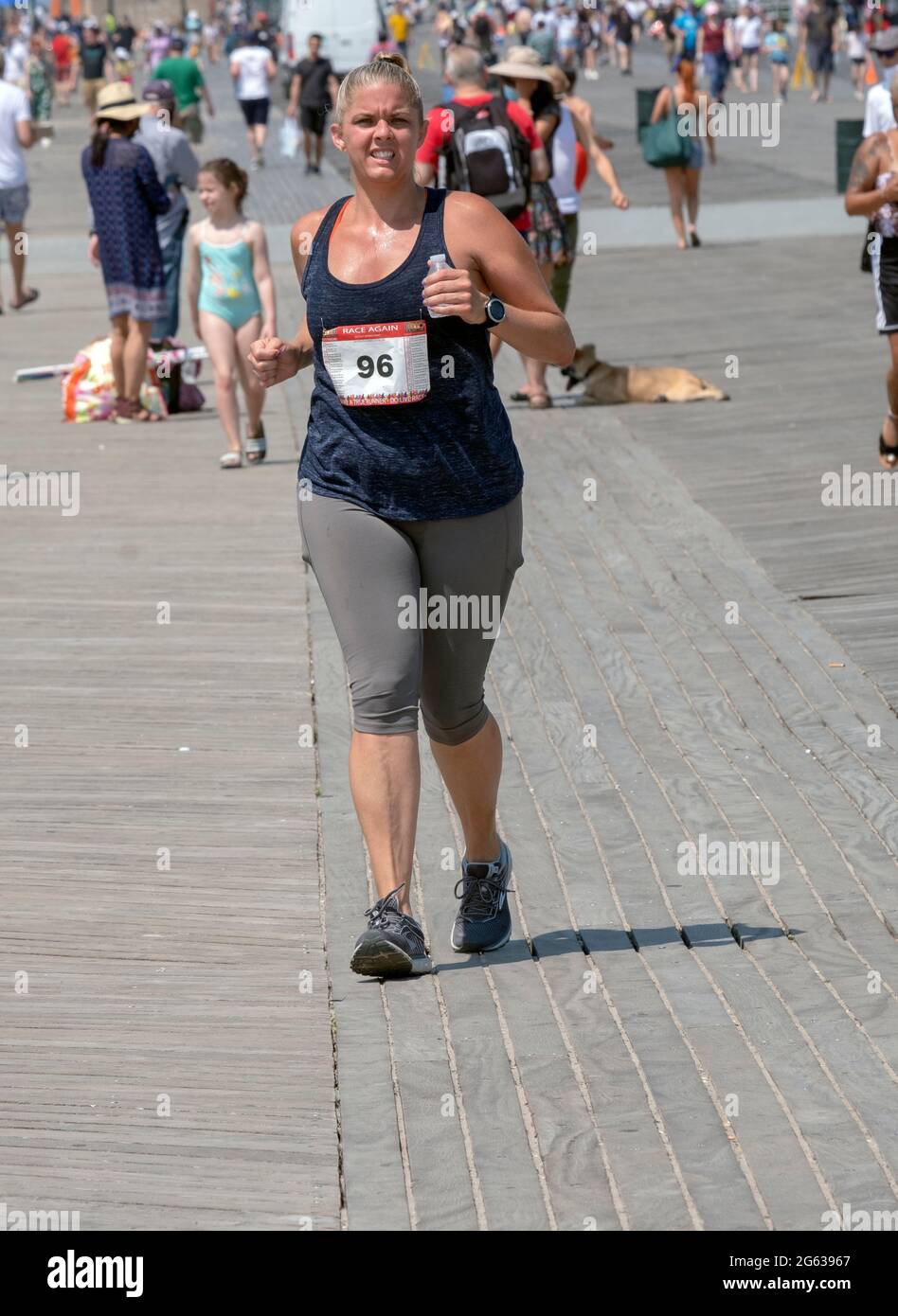 Eine Läuferin, die an einem heißen späten Frühlingstag an einem Halbmarathon-Langstreckenrennen teilnimmt. Auf der Promenade in Coney Island, Brooklyn, New York. Stockfoto