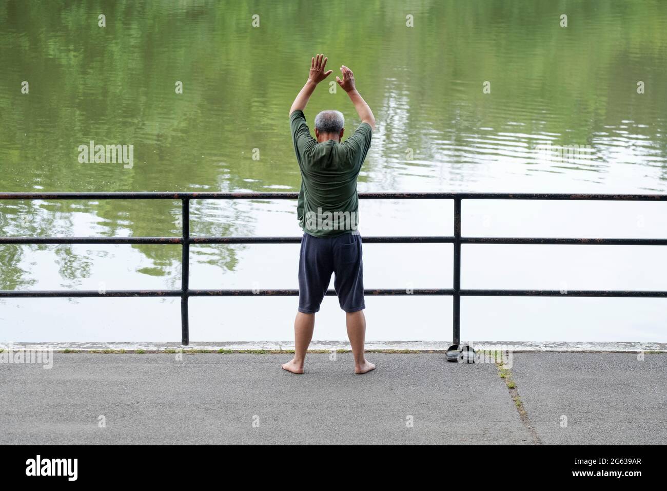 Ein älterer asiatischer Amerikaner macht Stretching-Übungen in der Nähe des Sees im Kissena Park, Flushing, New York. Stockfoto