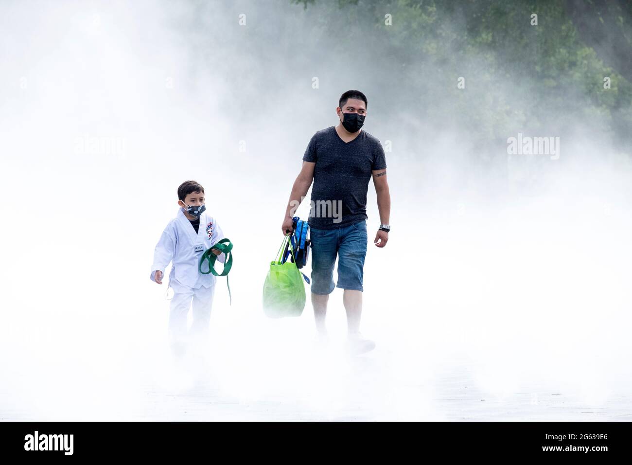Ein Vater und ein Sohn tauchen aus dem Brunnen der Messen auf, einem Nebelgarten, der einen aus der Weltausstellung 64 nachbildet. In Flushing Meadows Park, Queens, . Stockfoto