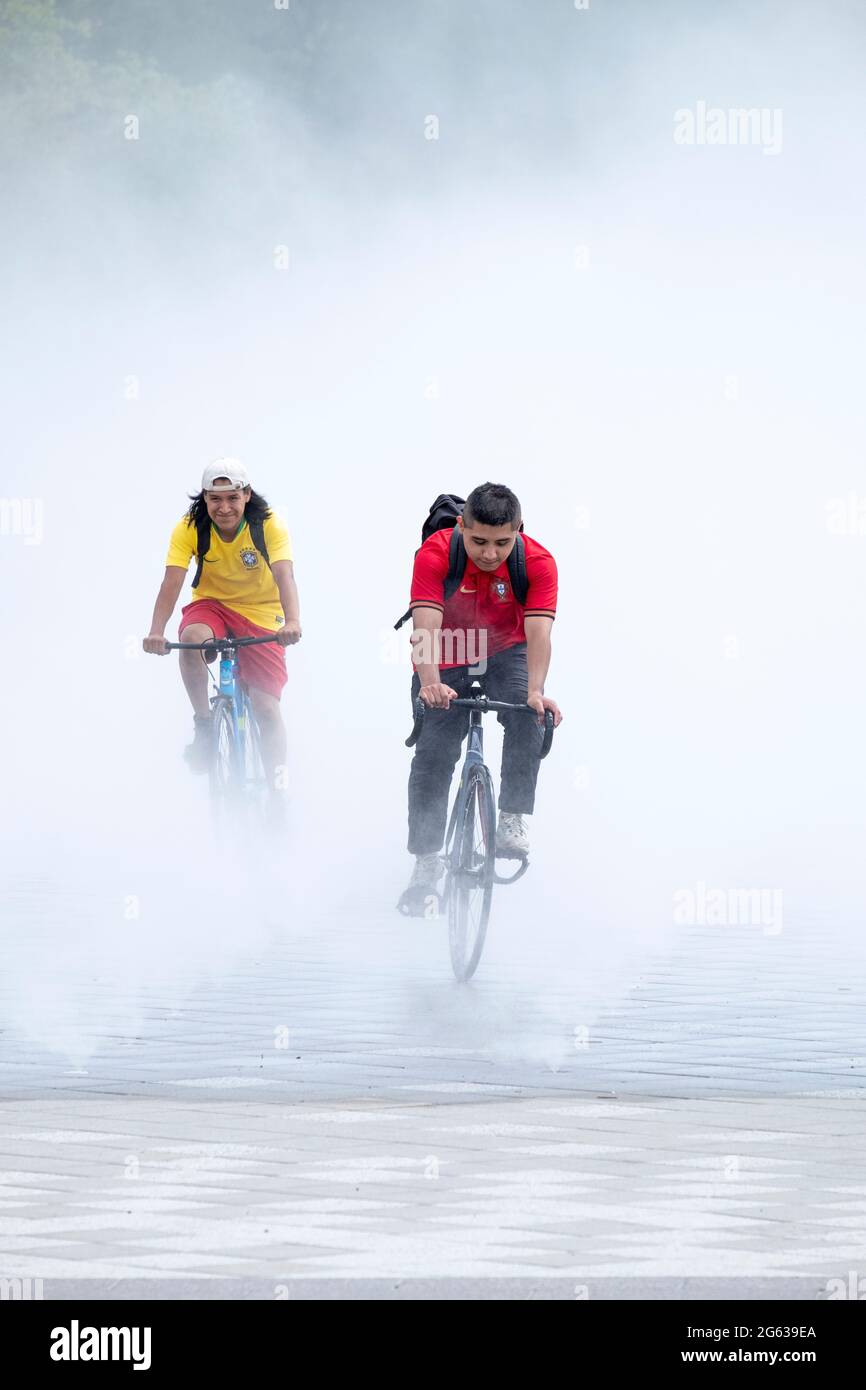 Motorradfahrer steigen aus dem Brunnen der Messen, einem Nebelgarten, der einen von der Weltausstellung 64 nachbildet. In Flushing Meadows Park, Queens, New York City. Stockfoto