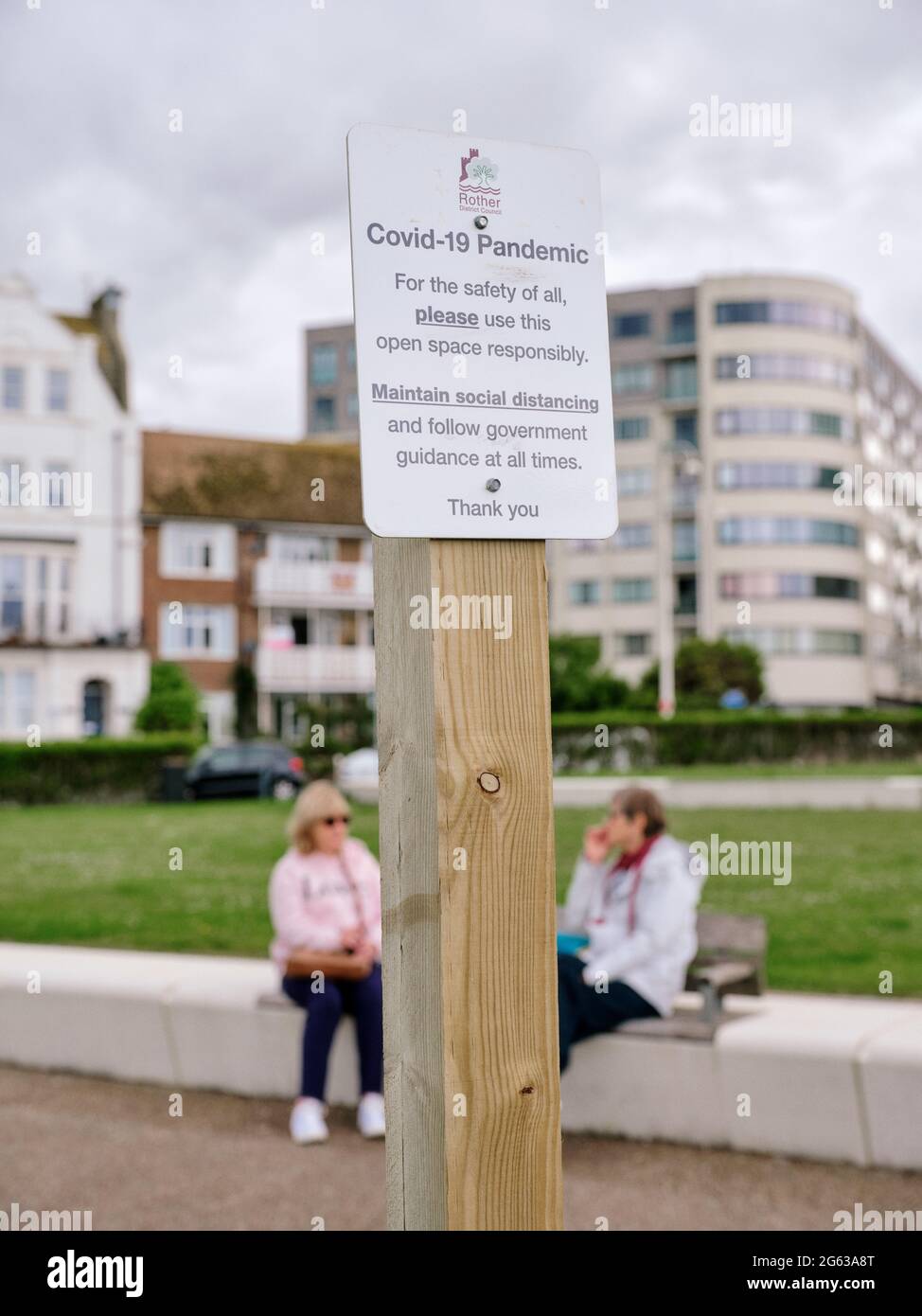 Covid-Alltag - zwei Freunde treffen sich im Freien, Covid 19 sichere soziale Distanzierung auf freiem Raum & Covid-Pandemiezeichen Bexhill Rother UK Juni 2021 Stockfoto