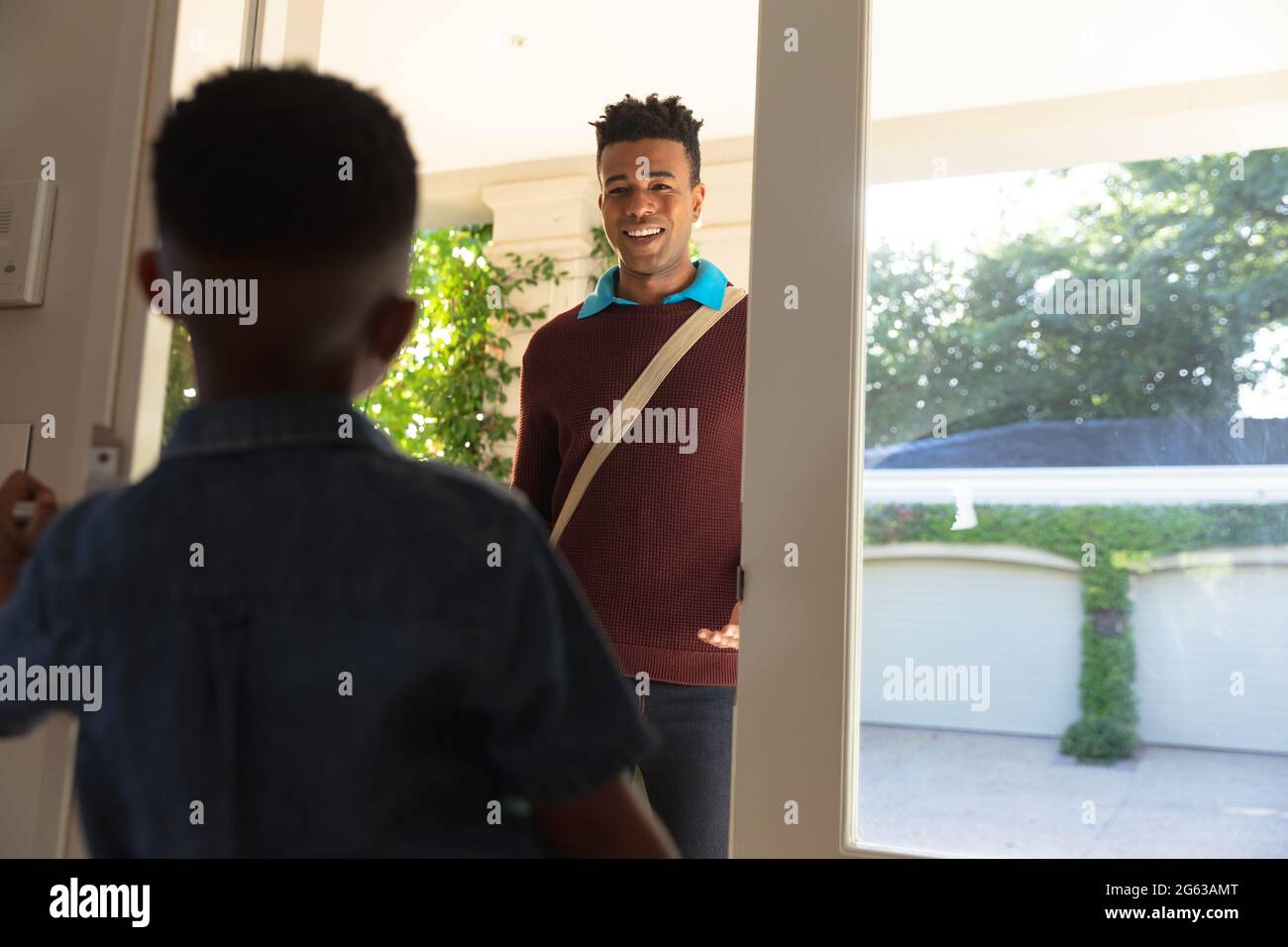 Glücklicher afroamerikanischer Vater mit Sohn zurück von der Arbeit lächelnd zu Hause Stockfoto