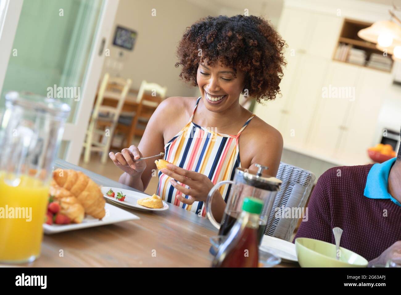 Glückliche afroamerikanische Mutter, die beim Familienfrühstück am Tisch saß und lächelte Stockfoto