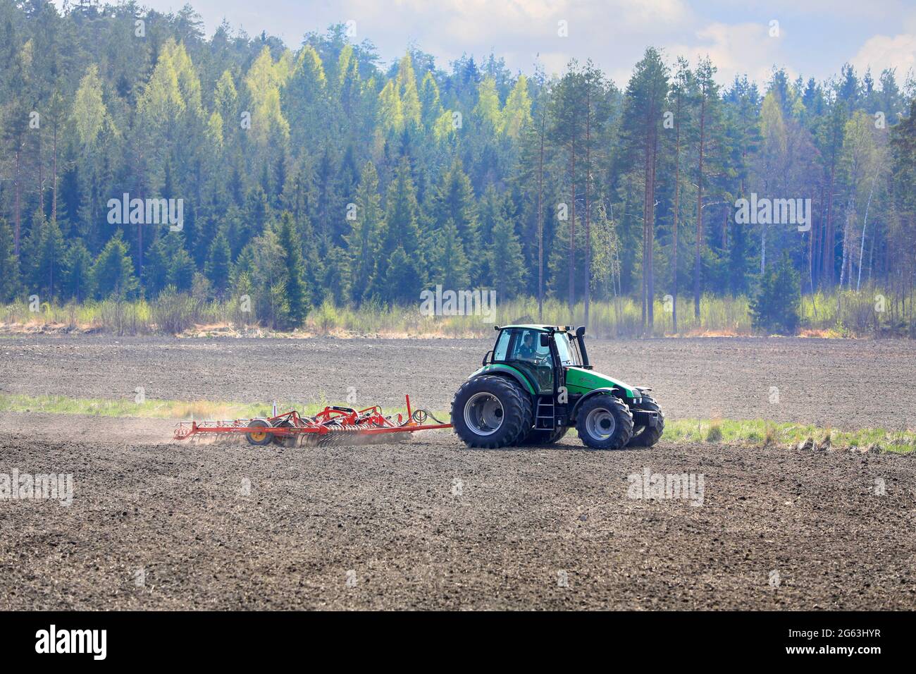 Landwirt kultiviert Feld mit grünen Deutz-Fahr Agrotron 135 Traktor und Vaderstad NZ aggressive Zinkenegge im Frühjahr. Salo, Finnland. 13.Mai 2021 Stockfoto