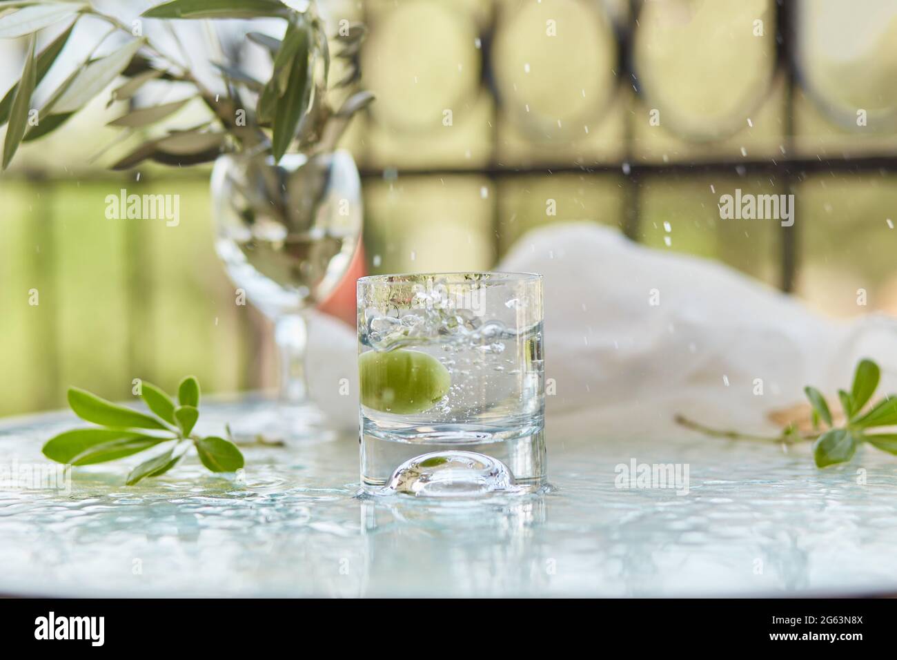 Sommer elegante Cocktails auf dem Hintergrund. Die dekorativen grünen Blätter blühen und der Zweig des Olivenbaums im Glas. Glyphe der Reinigung. Stockfoto
