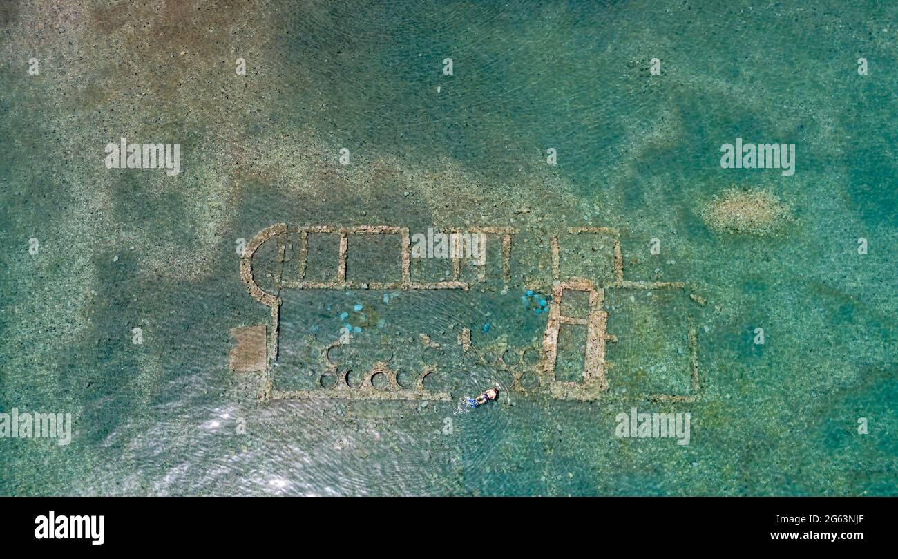 Alte versunkene Stadt Epidaurus bei Argolida, Griechenland Luftaufnahme, Drohne von oben nach unten. Griechisches Atlantis unter Wasser mit gut erhaltenen Ruinen, Wellenbrecher. Swi Stockfoto