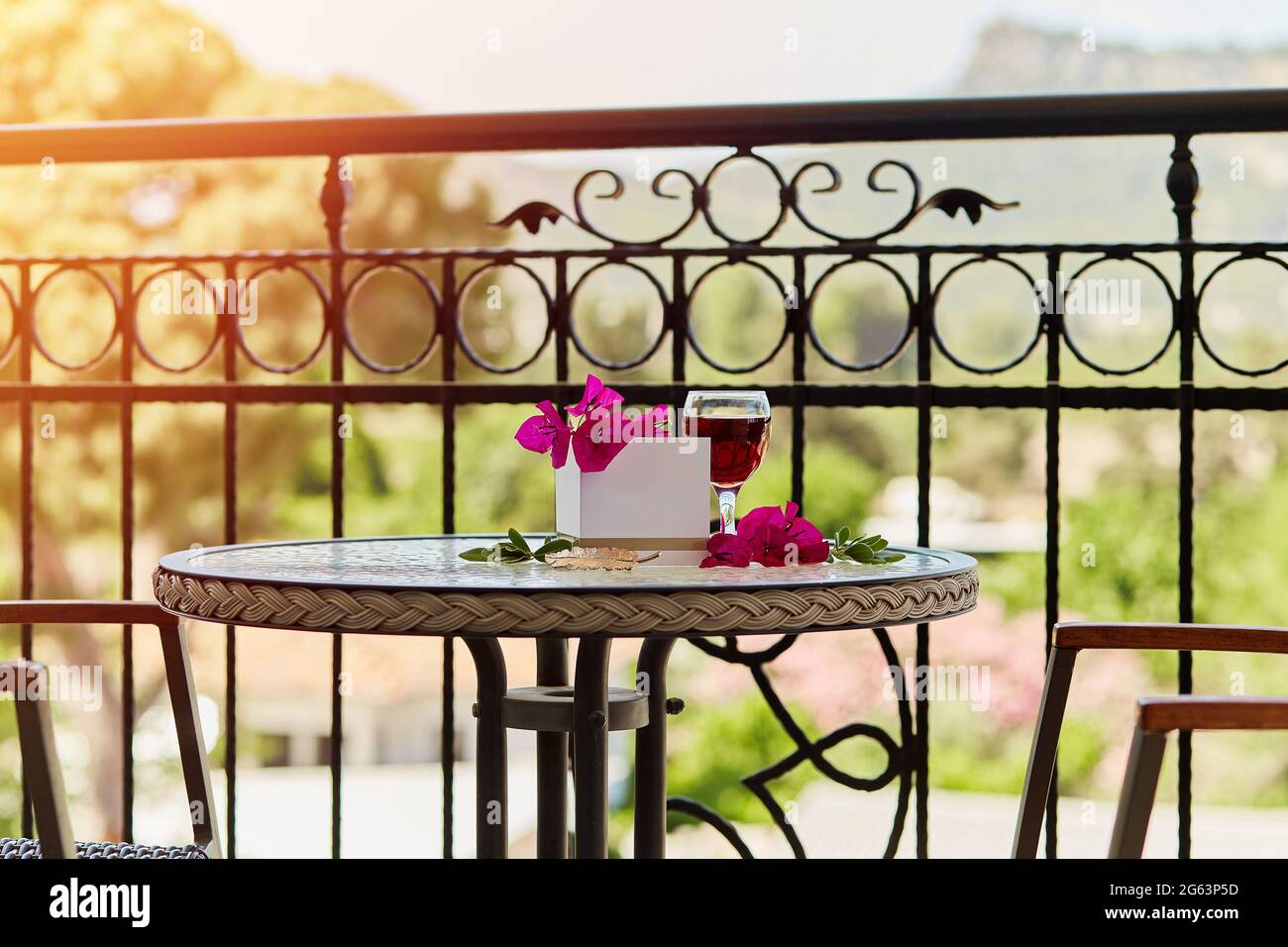 Elegantes Glas Rotwein. Dekorative rosa Blüten von Bougainvillea. Nachbau einer Postkarte oder Einladung. Festliches Weihnachtskonzept. Dekorative grüne Leine Stockfoto