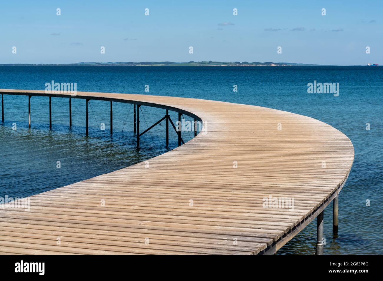 Eine geschwungene Holzpromenade führt in den blauen Ozean Stockfoto