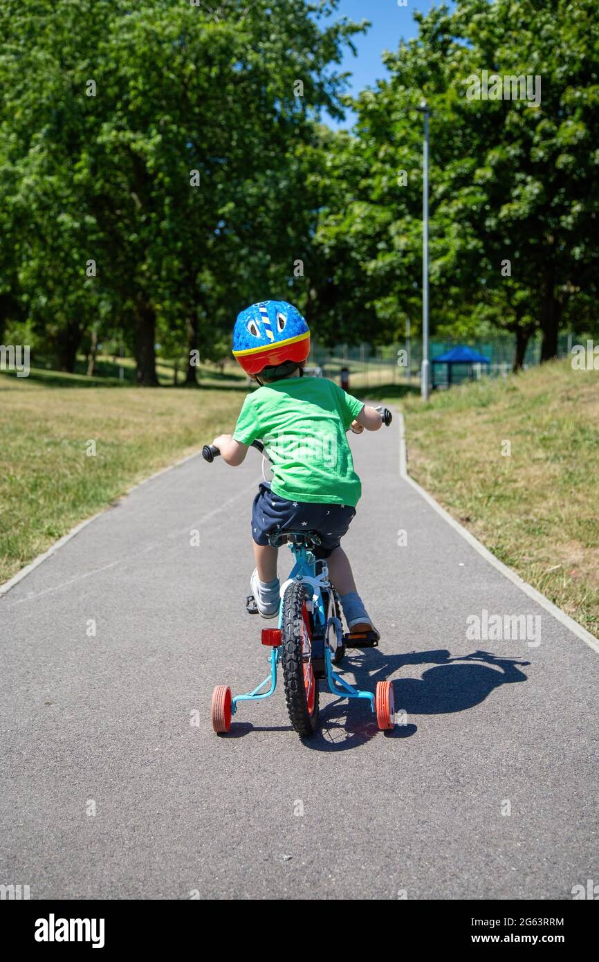 Ein kleines Kind, das mit dem Fahrrad durch einen Park fährt Stockfoto