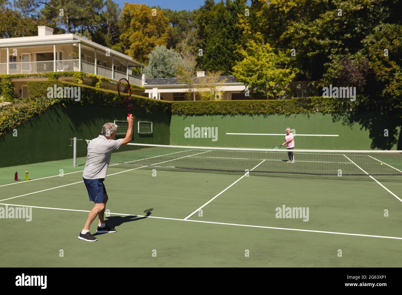 Ältere kaukasische Paare spielen gemeinsam Tennis auf dem Platz Stockfoto