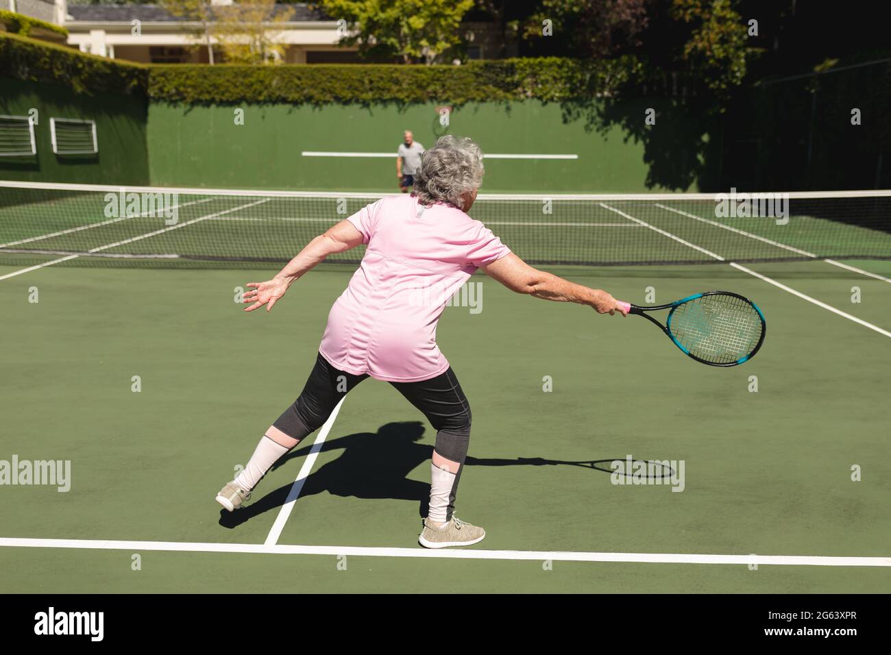 Ältere kaukasische Paare spielen gemeinsam Tennis auf dem Platz Stockfoto