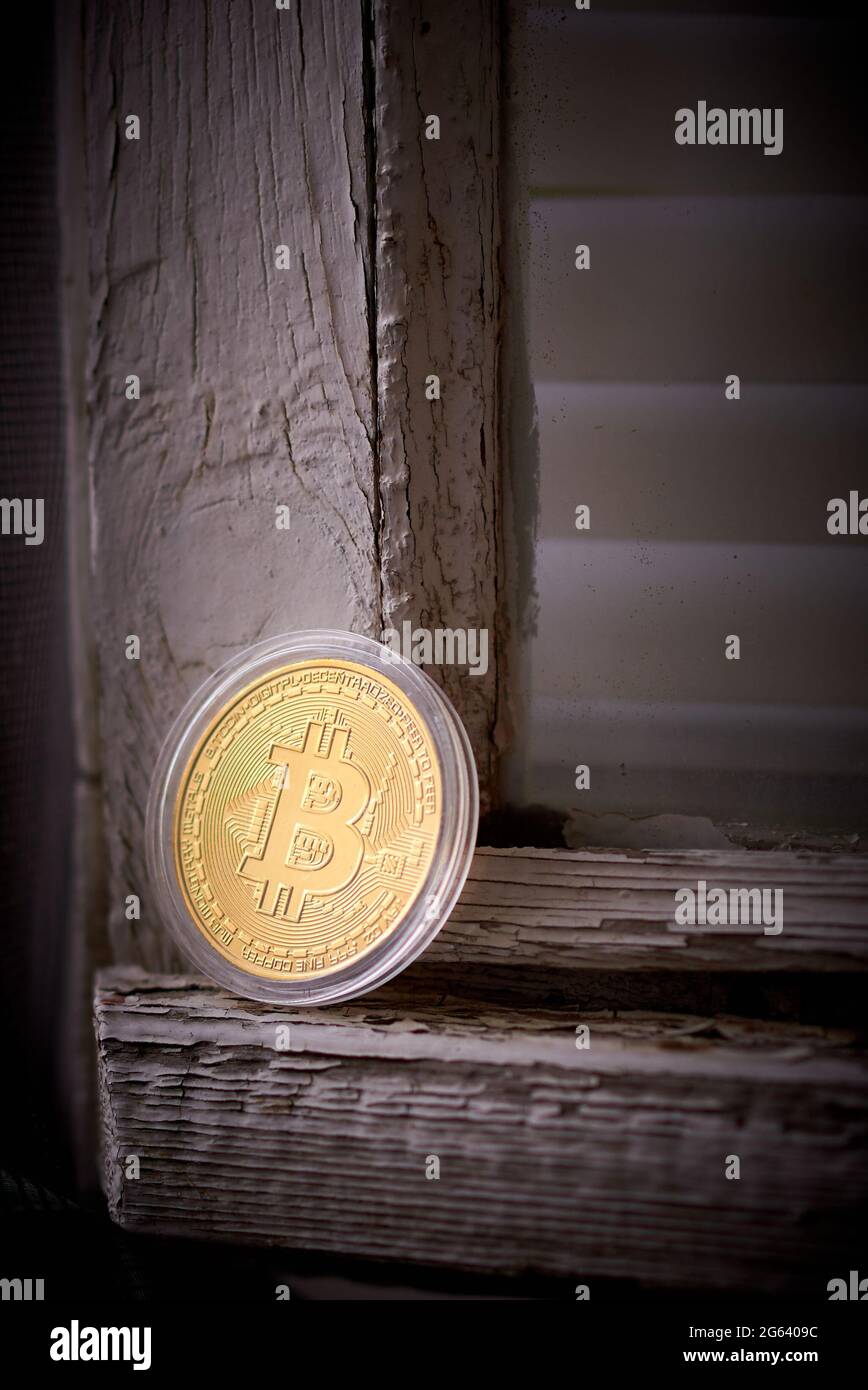 Bitcoin in einem Etui liegt auf einem alten Holzfensterrahmen. Dunkler Hintergrund Stockfoto
