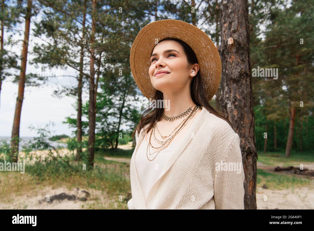 Fröhliche junge Frau in Sonnenhut lächelt im Wald Stockfoto