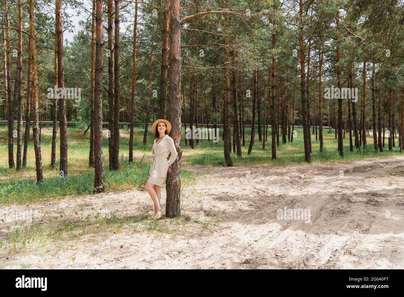 Volle Länge der fröhlichen jungen Frau im Strohhut im Wald stehend Stockfoto