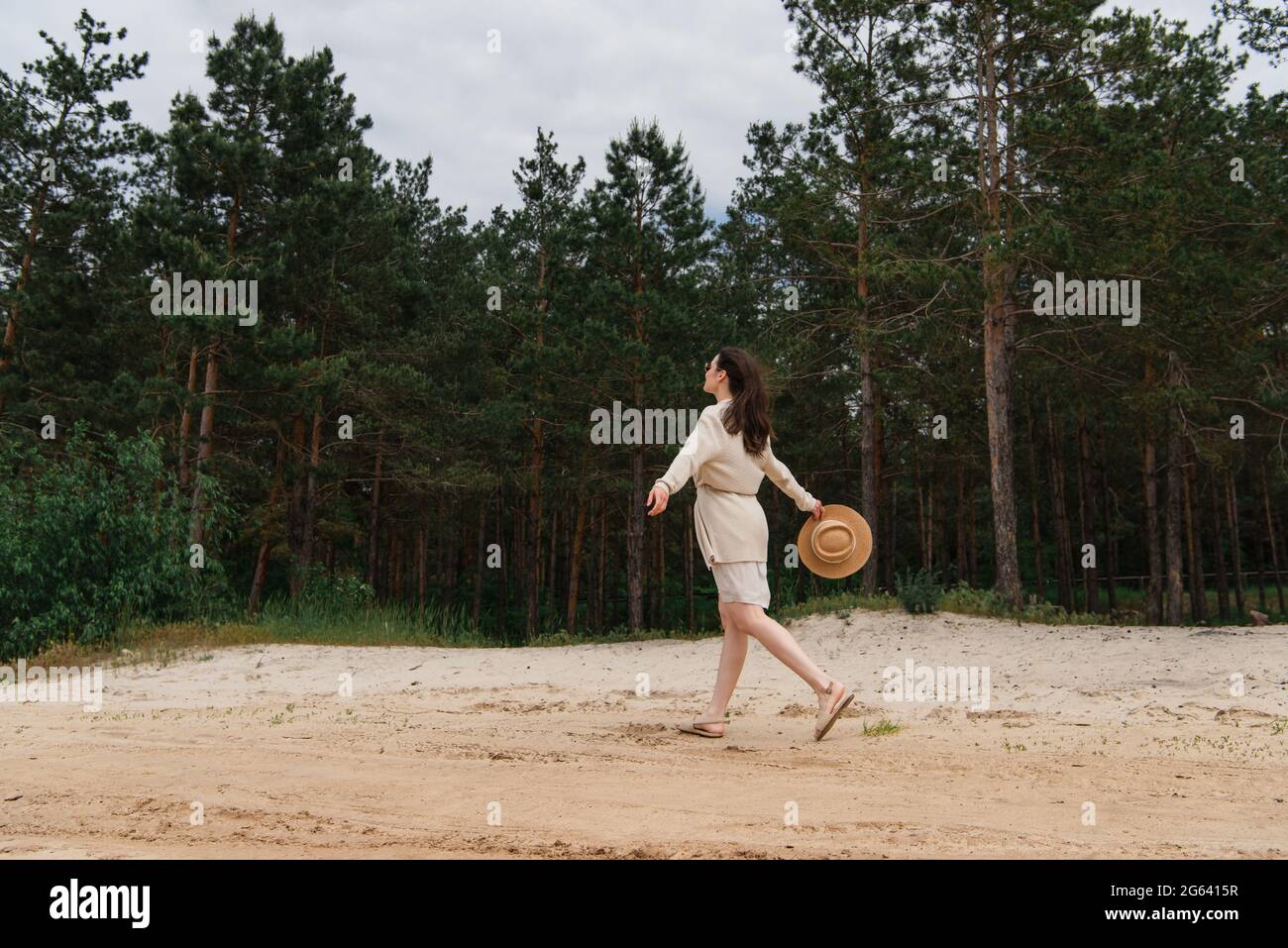 Volle Länge der Brünette junge Frau in Sonnenbrille mit Strohhut und Spaziergang in der Nähe von Wald Stockfoto