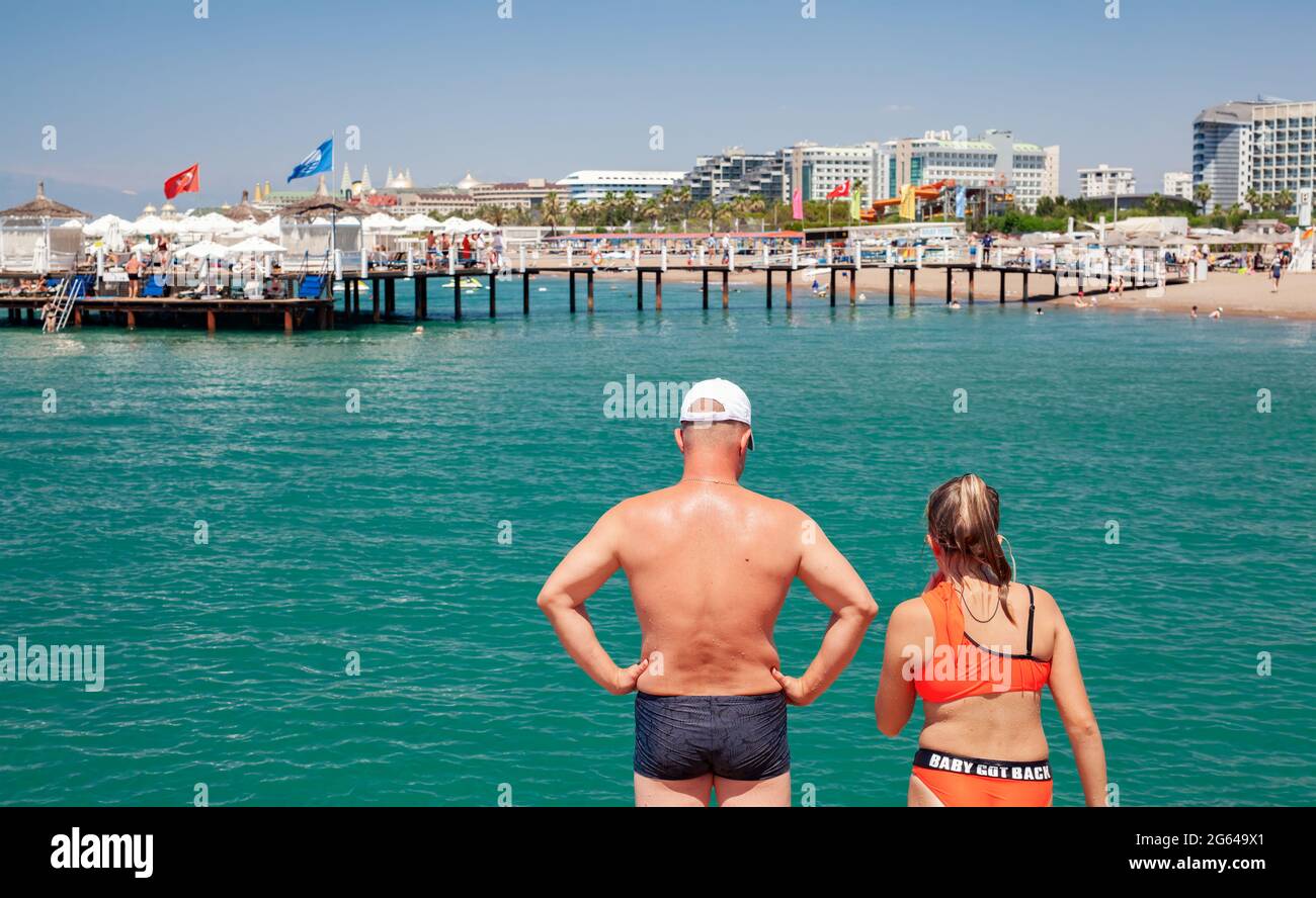 Antalya, Türkei-29. Juni 2021: Vater und Tochter machen sich bereit, im Sommer in Antalya vom Dock ins Meer zu springen. Verschwommenes Gerben von Menschen und Hotels Stockfoto