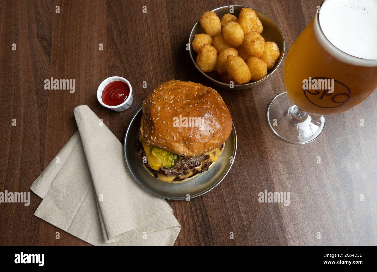 Ein Cheeseburger mit Tater Tots und einem Schoner Bier im Patty B's Burgers in der GPO Food Hall in Liverpool Stockfoto