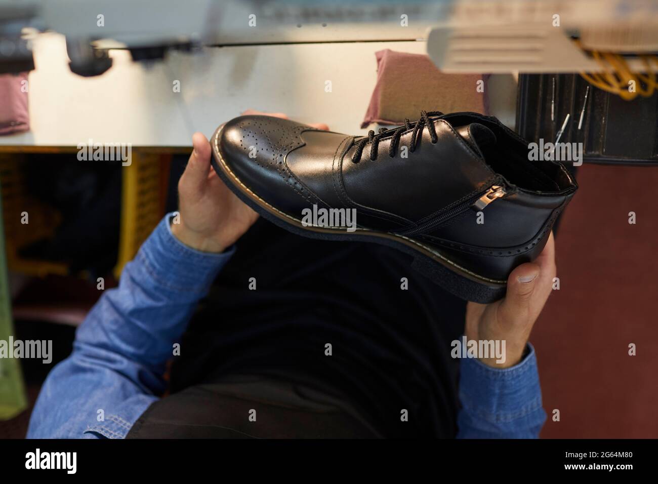 Nahaufnahme eines neuen schwarzen Lederstiefels in den Händen eines Schuhfabrikarbeiters Stockfoto