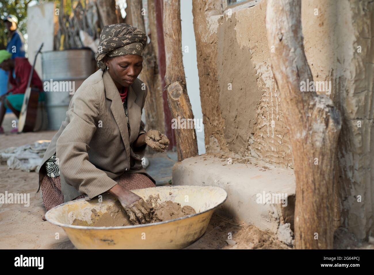 Eine Frau, die eine traditionelle Hütte verputzte. Tsetseng ist ein Dorf im Distrikt Kweneng in Botswana. Es befindet sich in der Kalahari-Wüste, 40 km nordöstlich von Kang. Botswana. Stockfoto