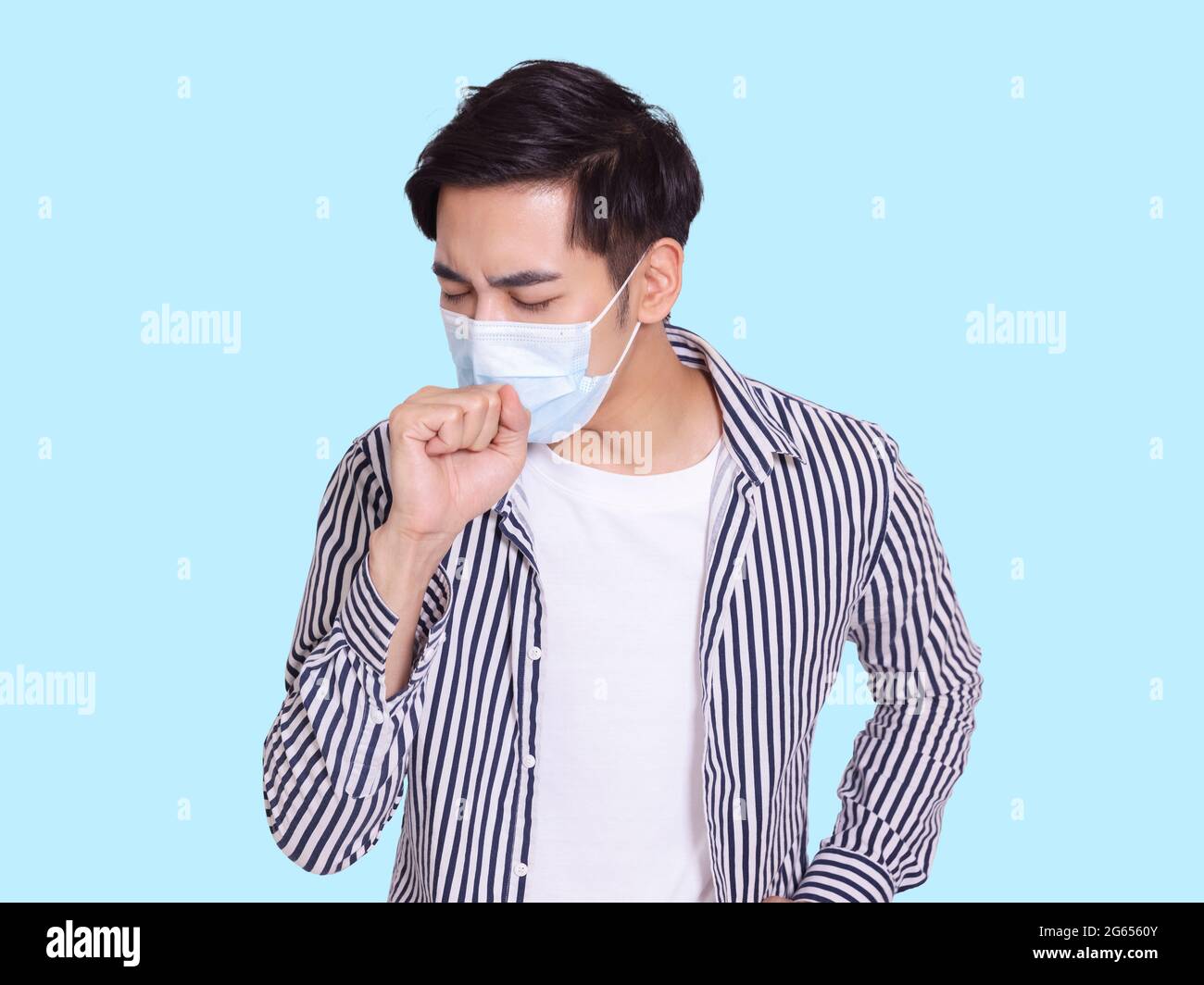 Der junge Mann hustet und trägt eine medizinische Schutzmaske, um Infektionen zu verhindern Stockfoto