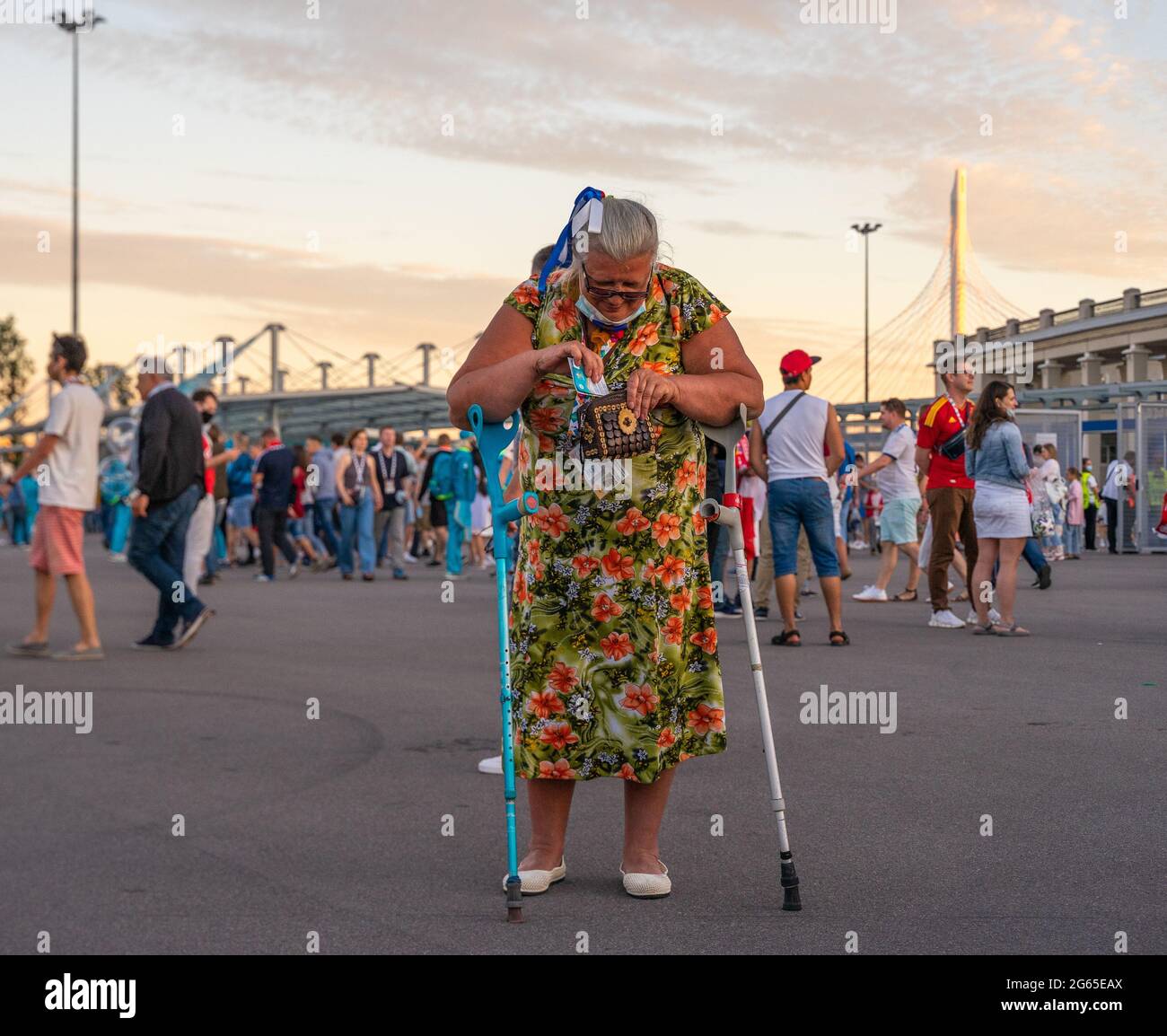 Ältere russische Fußballfan-Frau mit Unterarmkrücken, die ihr Game-Tag in die Geldbörse stecken, UEFA EURO 2020, St. Petersburg, Russland Stockfoto