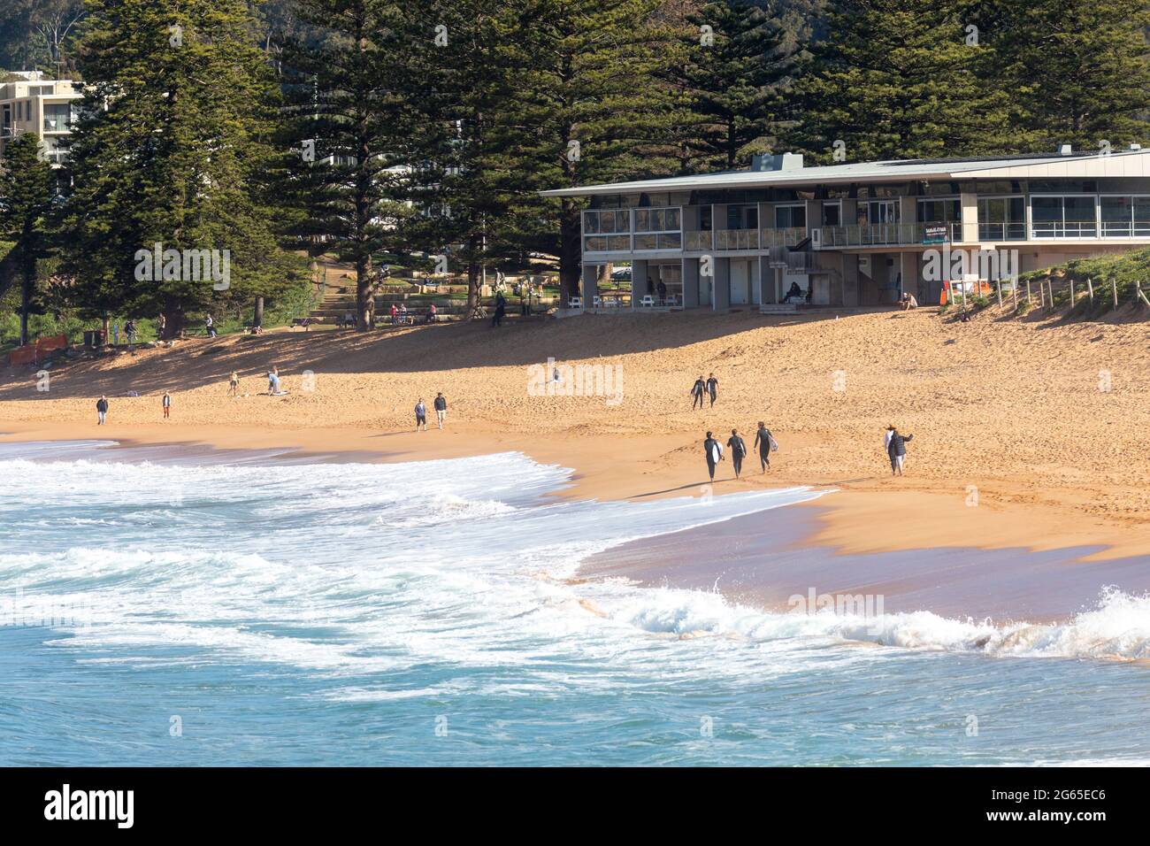 Australische Surfer tragen ihre Surfbretter am Avalon Beach in Sydney an einem sonnigen Wintertag, NSW, Australien Stockfoto