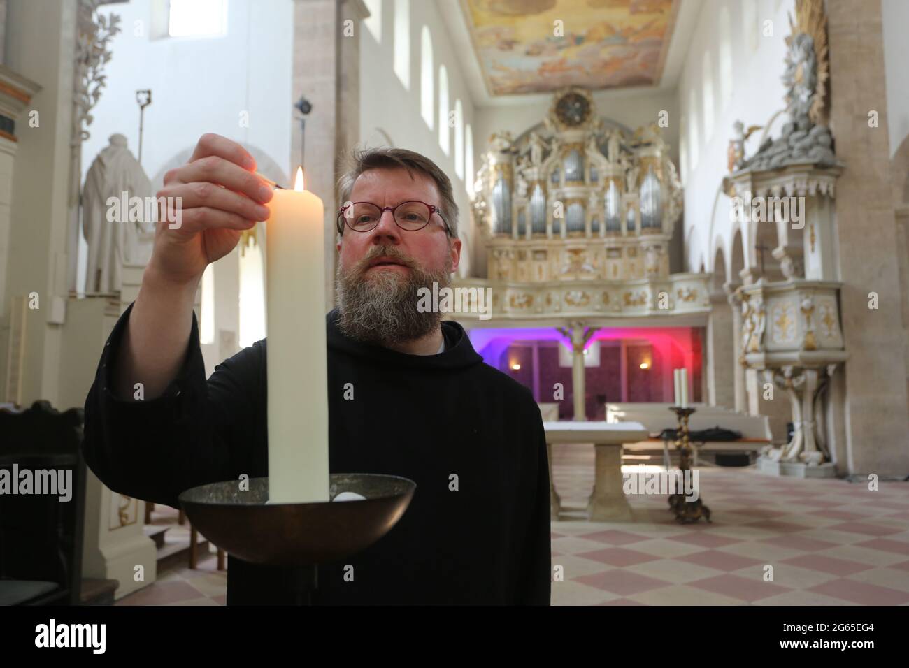 Dingelstedt, Deutschland. Juli 2021. Bruder Jakob Wilhelm zündet in der Klosterkirche im Kloster Huysburg eine Kerze an. Am Samstag wird der geistliche Leiter des Gast- und Konferenzhauses den Romanesikpreis 2021 entgegennehmen. Quelle: Matthias Bein/dpa-Zentralbild/ZB/dpa/Alamy Live News Stockfoto