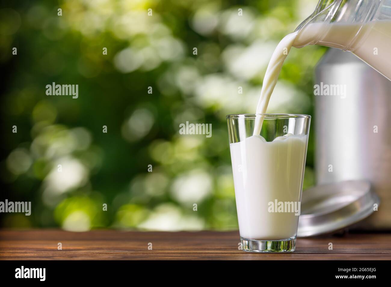 Milch aus dem Krug ins Glas im Freien gießen Stockfoto